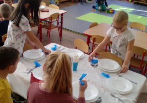 Dzieci kończące pracę nakrywania stołu.